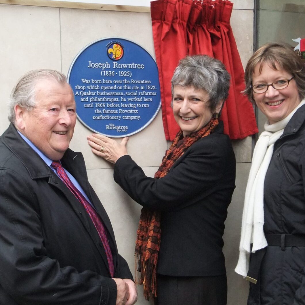 Three people unveil a plaque
